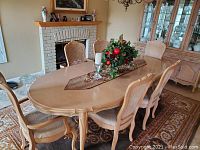 Oval dining table with extension set with table runner, shown in dining room setting with fireplace and china cabinet.