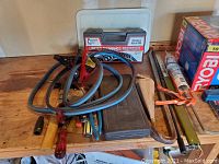 Workbench showing tire chains with tensioning handles, various screwdrivers and hand tools arranged on wooden surface.