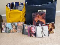 Two bags filled with CDs and several CDs displayed in front, showing variety of artists and albums.
