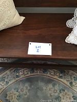 Dark wood antique bench close-up with label 'LOT 2' and floral rug beneath