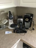 Photo showing Keurig coffee maker, KitchenAid mixer, 4-slice toaster, and cordless phones on kitchen counter.