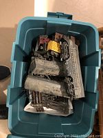 Plastic storage tub containing a model train set with locomotive, train cars, and track pieces.