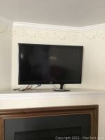 Samsung flat-screen TV on mantel/shelf with cables connected, showing front and slight left angle.
