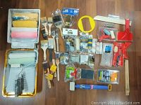 Overview of painting supplies including rollers, brushes, trays, scrapers and accessories on floor