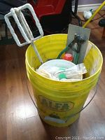 Yellow Alfa bucket holding paint mixer, trowels, and tile setting tools.