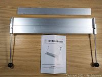 Full view of the disassembled metal bender including the main bending bar, base with handles, and included user manual.