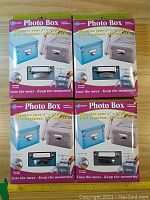 Four packages of KeepSafe photo boxes stacked, front view showing blue and gray boxes on packaging