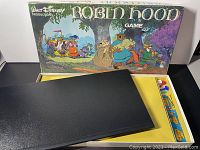 Photo showing Walt Disney Robin Hood board game box cover, game board, and pieces inside the box