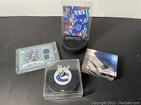 Full set of Vancouver Canucks collectible lot showing signed puck, jersey card, logo paperweight, and puck holder