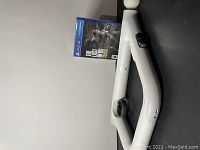 Sealed PlayStation 4 game The Last of Us Remastered case propped against a light gray PlayStation 2 Time Crisis gun controller on a dark surface.