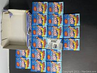 Seventeen unopened 1991-92 O-Pee-Chee OPC NHL hockey wax packs arranged alongside an open box.