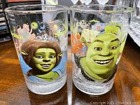 Front view of two glass tumblers showing Shrek and Princess Fiona images and colorful decorations