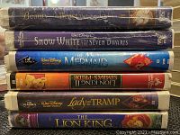 Stack of VHS tapes featuring Beauty and the Beast The Enchanted Christmas (NIB), Snow White and the Seven Dwarfs Platinum Edition (NIB), Snow White and the Seven Dwarfs, The Little Mermaid, The Lion King, Lady and the Tramp, and The Lion King.