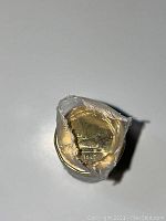 Close-up photo of one end of the coin roll showing the year 1987 and loon design of the coin inside the plastic wrapping.