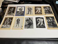 Lot of 10 black and white vintage Beehive hockey pictures laid out on white surface showing various player poses and mounts.