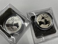 Front view of both coins in clear holders showing the 2011 Canoe and 2012 Reindeer designs with inscriptions and denomination.