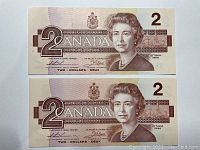 Front view of both 1986 Canadian $2 banknotes showing Queen Elizabeth II portrait and denomination markings.