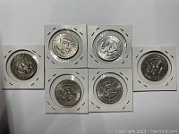 Front view of 6 Kennedy Half Dollar coins encased in holders showing reverse side Presidential Seal design with details.