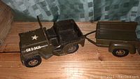 Side view of vintage Tonka army jeep linked to trailer showing paint, decals, and condition.