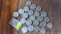 Photo of 22 Indian Head Nickels spread out on a wooden surface along with a small note indicating 3 coins from 1935 and 19 from 1936.