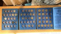 Blue blue coin collection folder with 30 nickel coin slots, most filled.