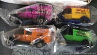 Four Kellogg's vintage promotional Matchbox type trucks in original sealed plastic bags, showing colorful cereal branding on each vehicle.