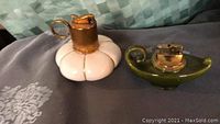 Photo showing two vintage ceramic lamp style lighters, one white pumpkin-shaped and one olive green dish-shaped with gold-tone lighter tops