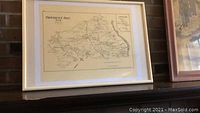 Framed reproduction map of Fairfax County from 1878 hanging on wall above mantelpiece. White frame and clear glass visible.