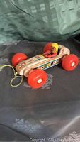Vintage Fisher-Price Bouncy Racer wooden pull toy shown from a front angle on fabric surface.