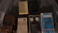 Three vintage transistor radios displayed including the Transonic radio with original box, RCA radio, and Channel Master radio with leather case.