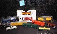 Overall lot of model trains arranged against black background showing various cars and locomotive.