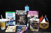 Photo showing the full array of Star Wars collectibles included: two Star Wars Legacy comic books, Clone Wars read-along book, the Solo cup, Pop! vinyl figure in box, Chewbacca party box, stickers, and cards.
