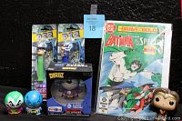 Photo showing the complete lot including two PEZ dispensers, two small Batman figures, one boxed Funko Dorbz vinyl figure, one Funko Pop Wonder Woman figure, and a 1983 Batman comic book.