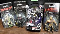 Four horror-themed action figures sealed in original packaging, displayed against a black background.
