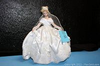 Full view of Cinderella Bride doll in satin and lace wedding gown with intricate details and black display stand.
