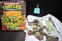 Photo showing Teenage Mutant Ninja Turtles collectors case with artwork of turtles and children's hoodie with TMNT graphic and text 'MAD SKILLS'.
