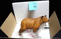 Wood-carved bear figurine in original white box with foam padding and tags.