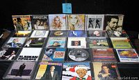 Photo showing various CD jewel cases with visible album covers from multiple artists including Hanson, Clint Black, Jessica Simpson, Stone Temple Pilots, Il Divo