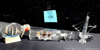 Photo showing three vintage ships: two ships encased inside glass bottles and one silver wire ship sculpture