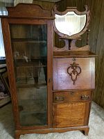 Front view of tiger oak secretary desk with attached glass-front bookcase and carved mirror