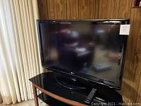 Front view of LG 42-inch flat screen TV with remote on stand