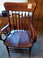 Front view of antique courthouse chair showing curved armrests, vertical back slats, wooden contoured seat, and original finish patina.