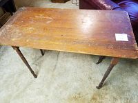 Top surface of an antique maple sewing table showing its rectangular shape and worn finish.