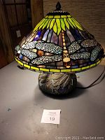 Full view of lamp showing stained glass shade with dragonfly motif and metal base