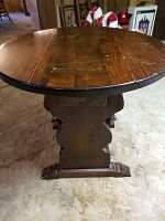 Side view showing round tabletop, pedestal base with shaped supports and feet.