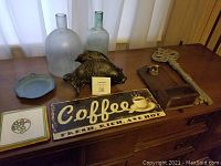 Overview of the box contents showing the carved wooden fish, glass bottles, coffee sign, metal key, ceramic plates, and bottle opener unit.