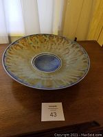 Top view of a round pottery bowl with a mottled greenish-brown glaze, showcasing a slightly concave form and a diameter of about 14.5 inches.