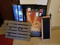 Lot showing three black 24x36 poster frames alongside barn door-style wooden picture holder and vertical wooden framed chalkboard with rope hanger