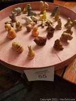 Mini porcelain animal figurines arranged on a pink tray, showing various animals such as dogs, birds, and rabbits.