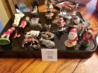 Wide view showing majority of assorted antique and collectible figurines on black tray with wood floor background.
